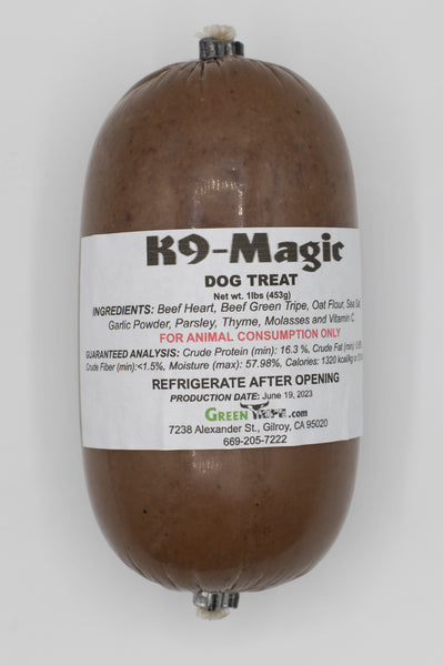 A rolled up treat labeled 'K9 Magic Dog Treat' with visible ingredients such as beef heart, beef green tripe, oat flour, sea salt, and parsley.